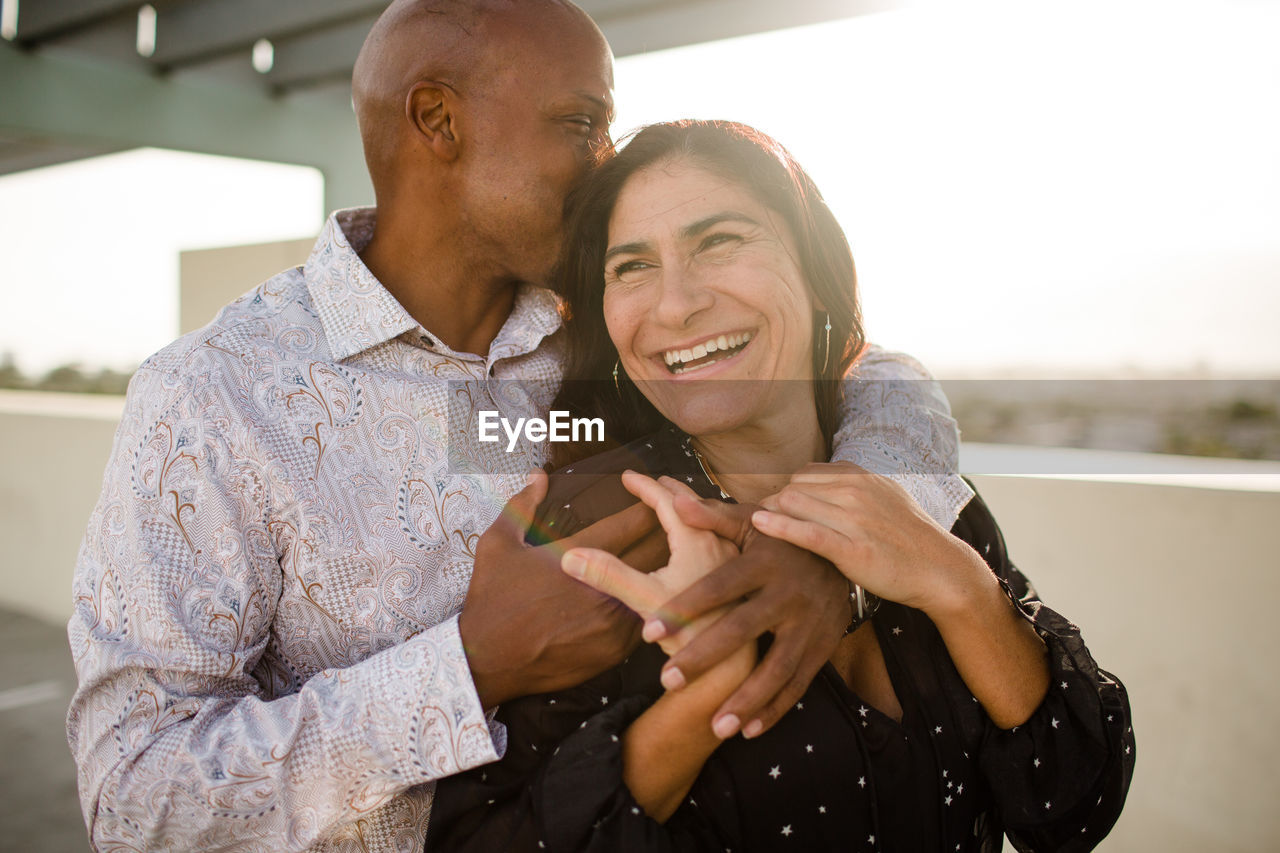 Multiracial late forties couple embracing at sunset in san diego