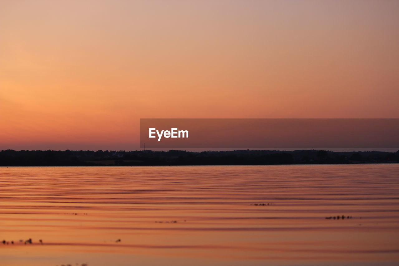 Scenic view of lake against orange sky