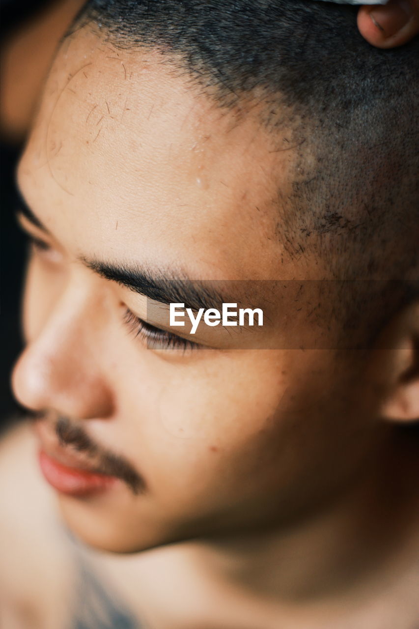 Close-up of man with shaved head looking away