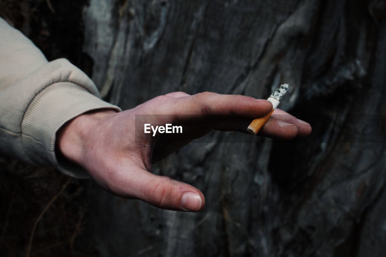 Hand that holds a cigarette in the forest