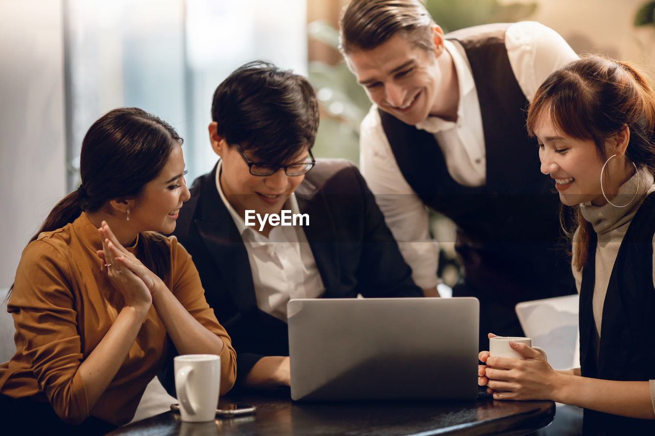 Business people brainstorming while looking at laptop in office