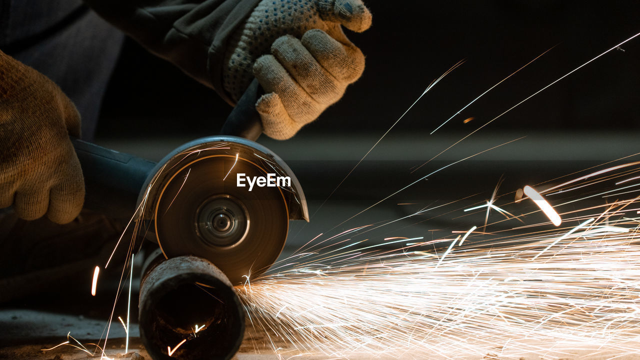 Cropped hands of man cutting metal in workshop