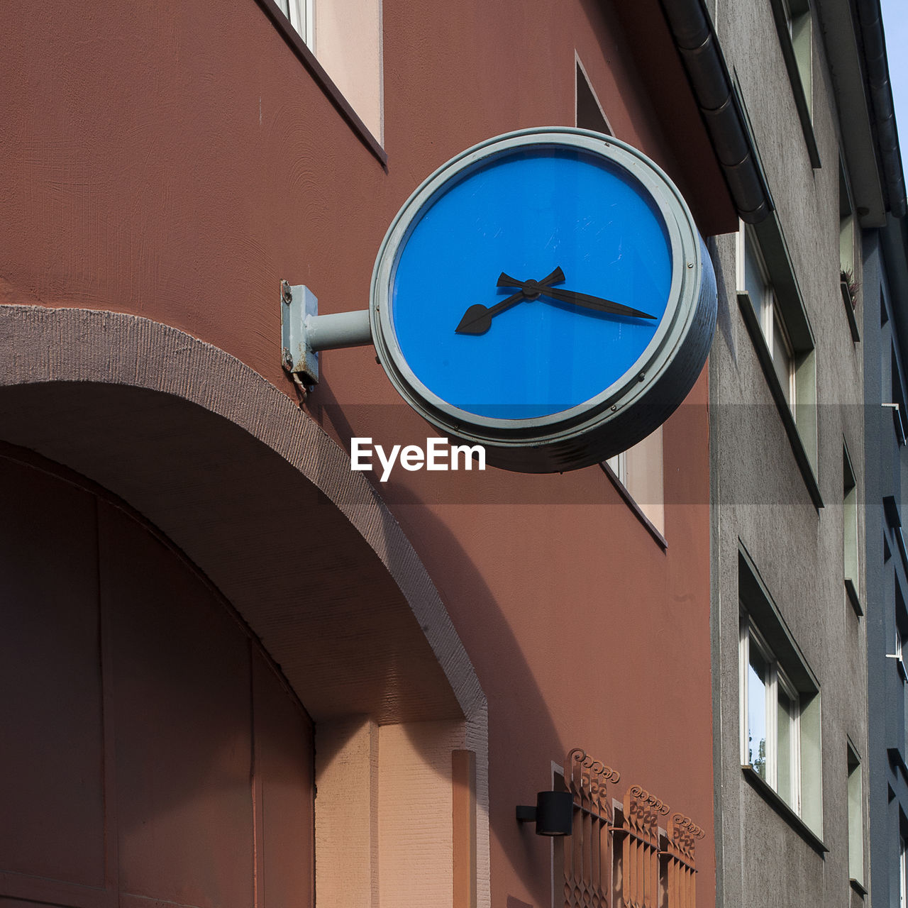 Low angle view of buildings with a clock against clear blue sky