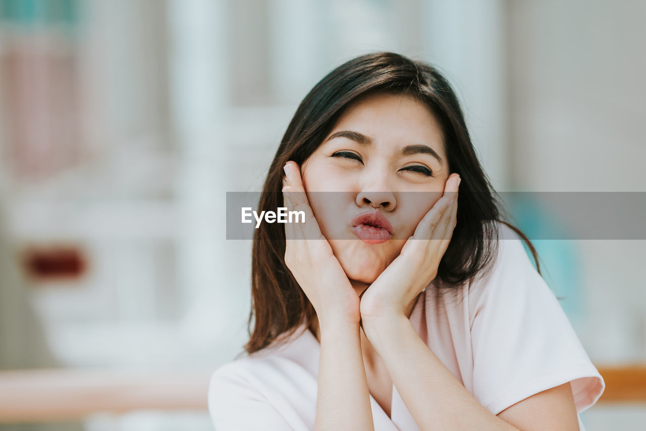 Close-up portrait of young woman puckering lips at home