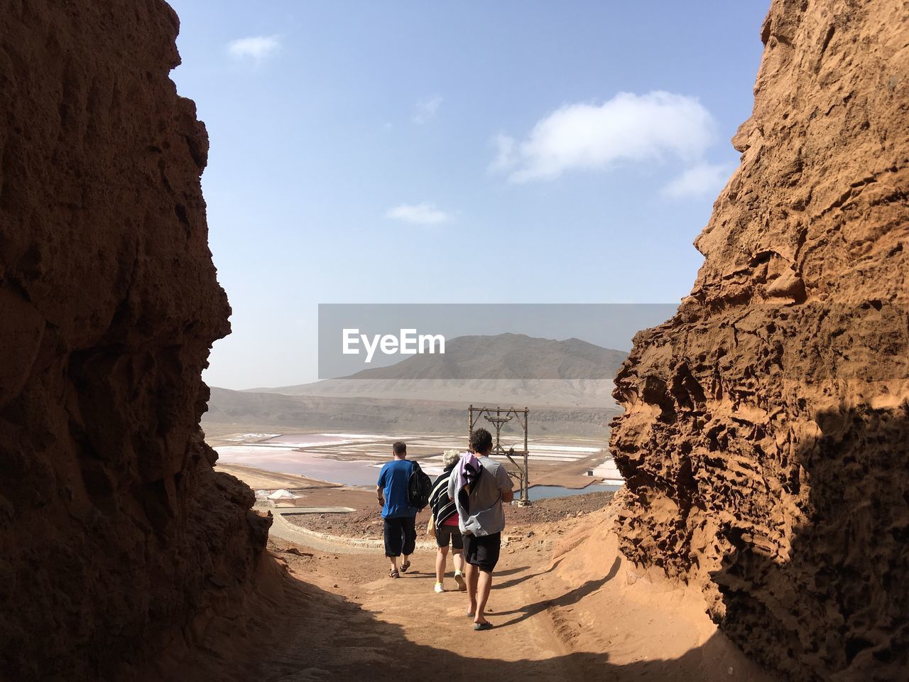 REAR VIEW OF PEOPLE WALKING ON ROCK FORMATIONS