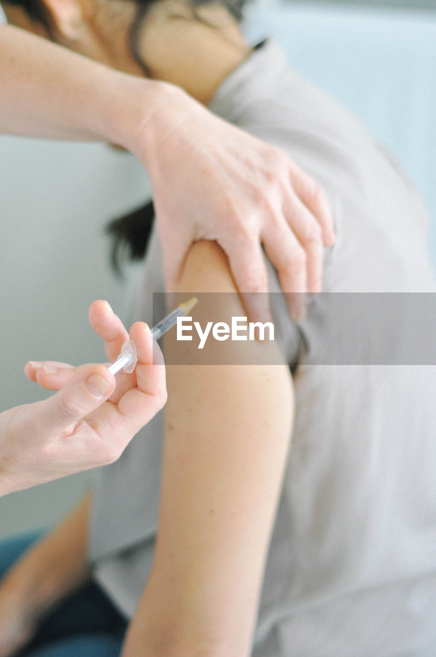 Cropped image of doctor injecting patient at hospital