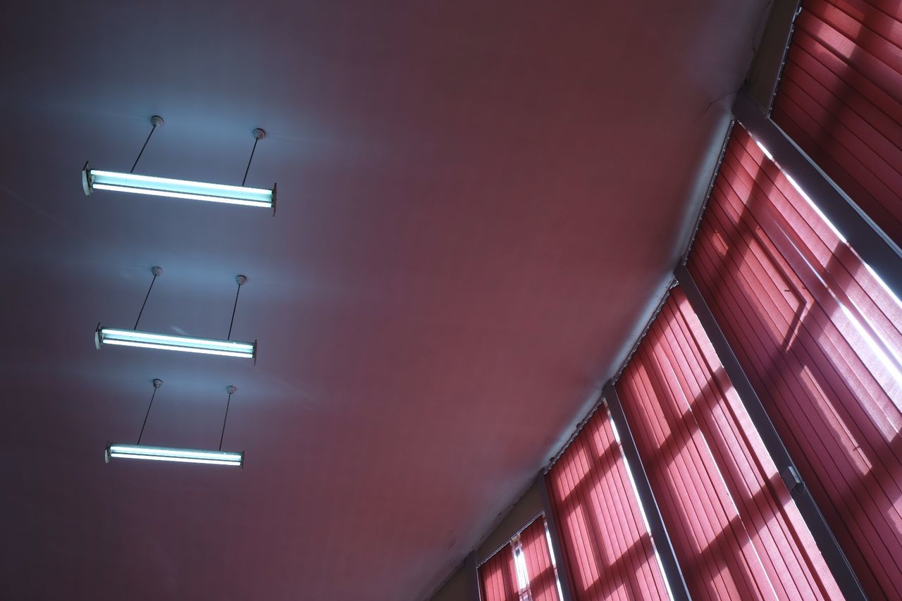 Low angle view of illuminated fluorescent lights hanging from ceiling