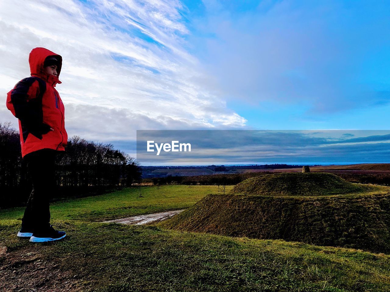 MAN STANDING ON FIELD AGAINST SKY DURING SUNRISE