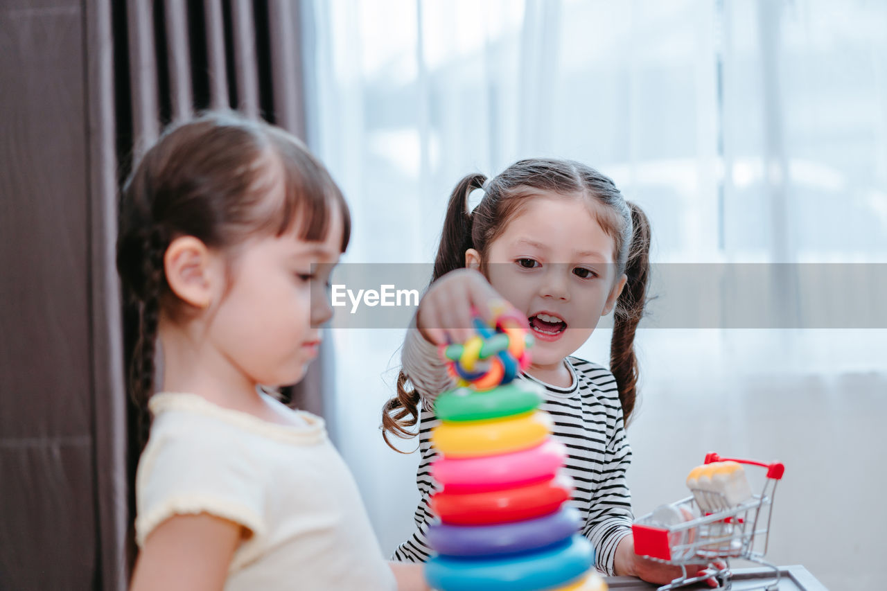 Sisters playing with multi colored toys at home