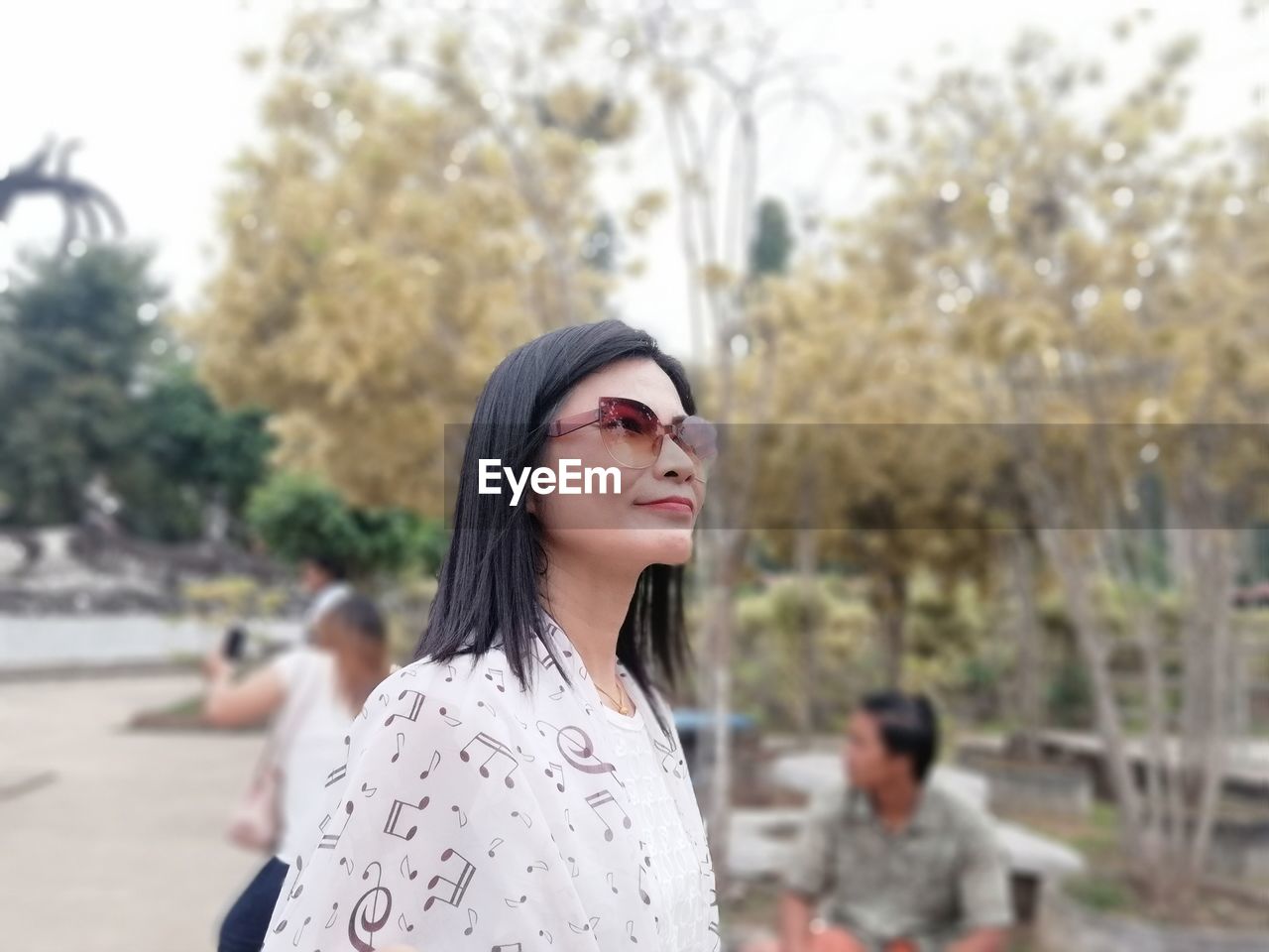 Woman wearing sunglasses against trees