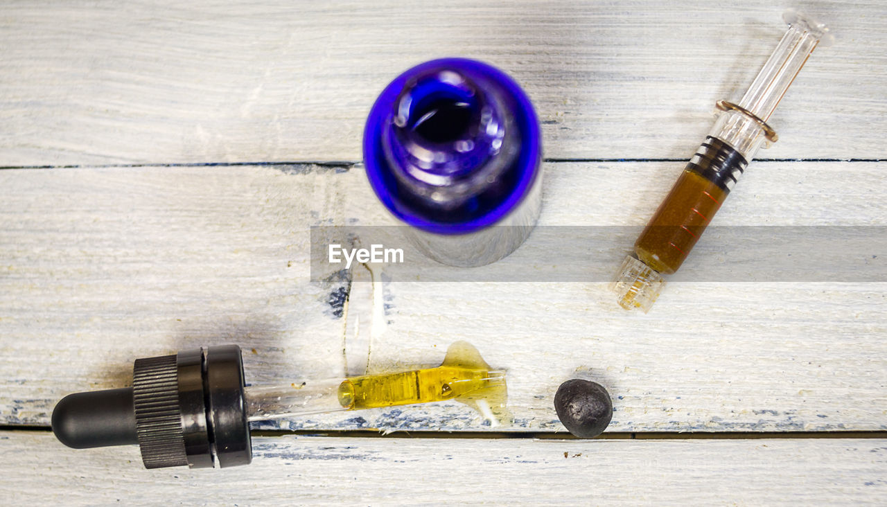 Close-up of syringe with medicine bottle on table