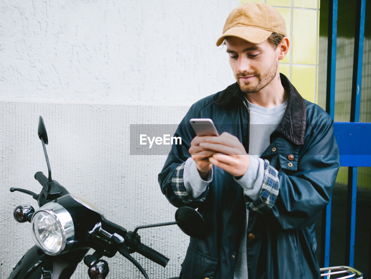 Young man using mobile phone by scooter