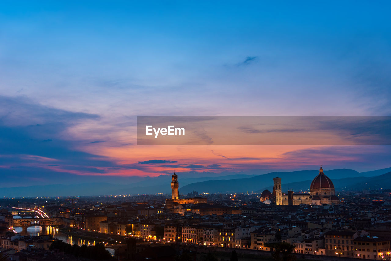 HIGH ANGLE VIEW OF ILLUMINATED BUILDINGS AGAINST SKY DURING SUNSET