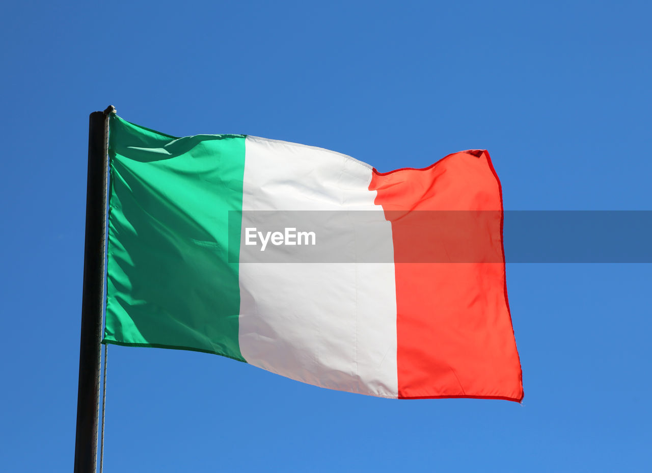 Big italian flag waving in blue sky with vivid red and white green colors