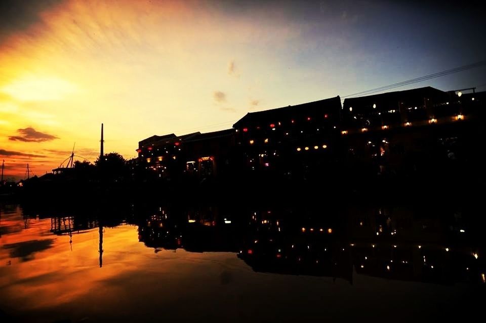 Reflection of silhouette buildings in lake at sunset