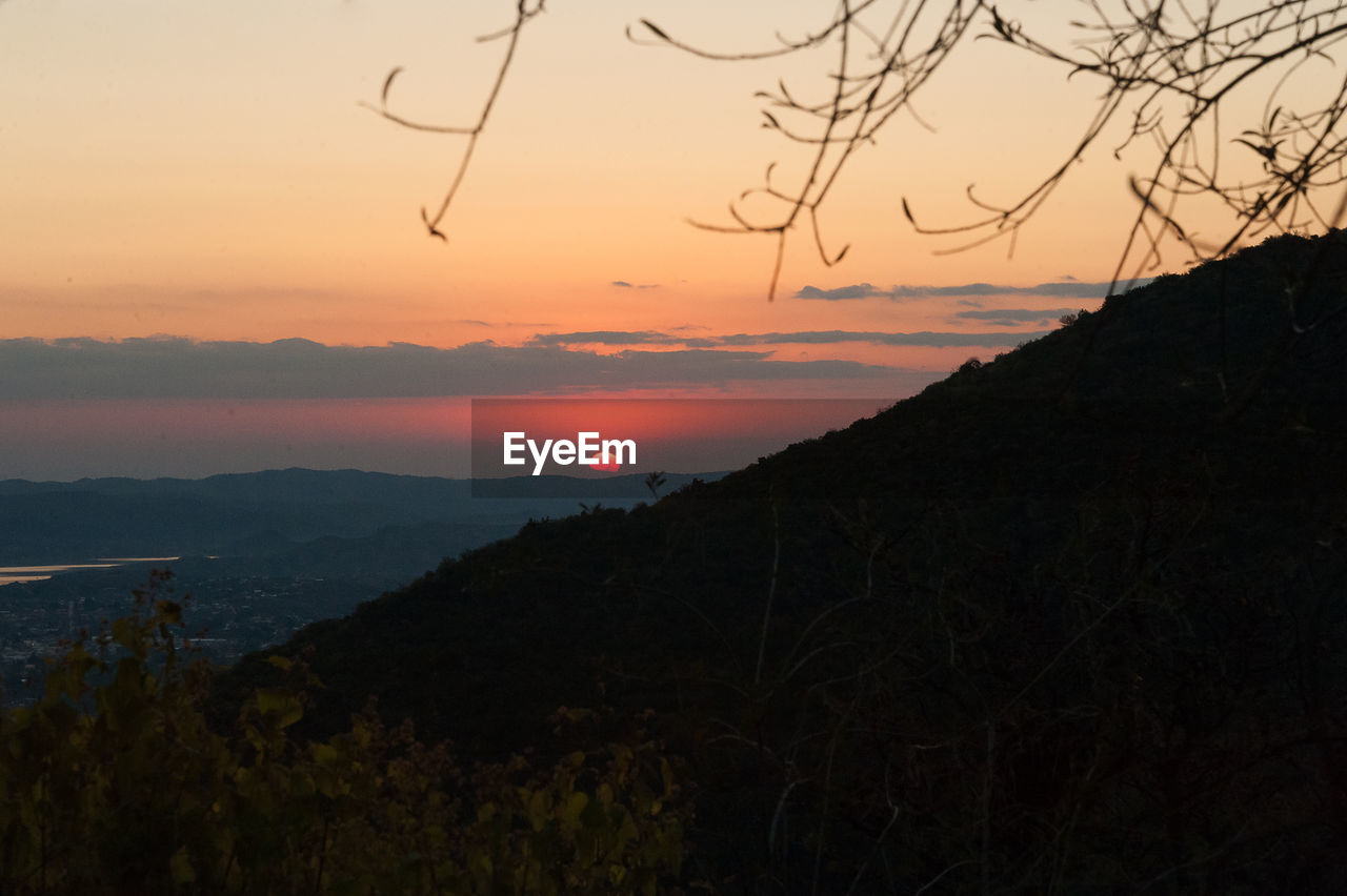 SCENIC VIEW OF SILHOUETTE MOUNTAINS AGAINST SKY AT SUNSET