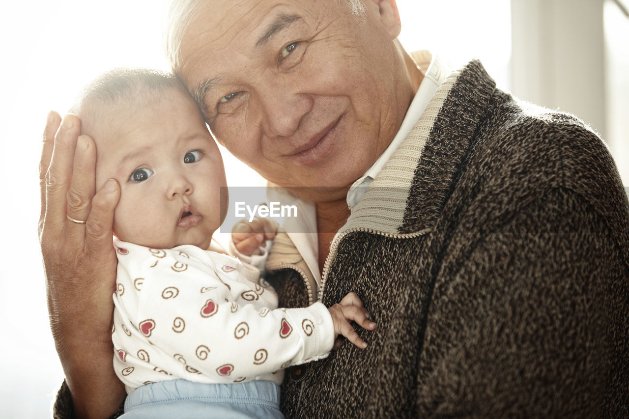 Portrait of happy grandfather head to head with his granddaughter