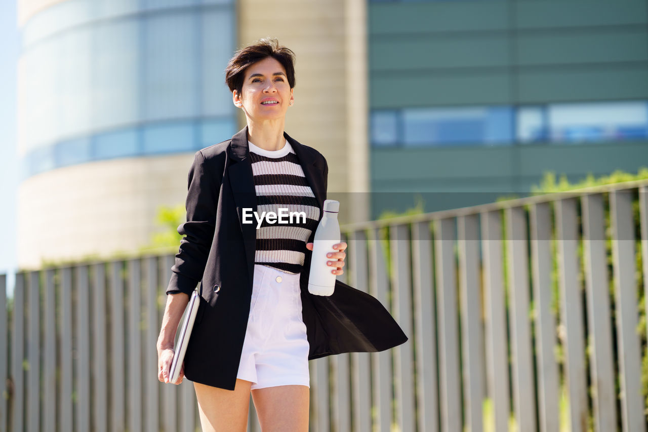 portrait of young woman standing against building