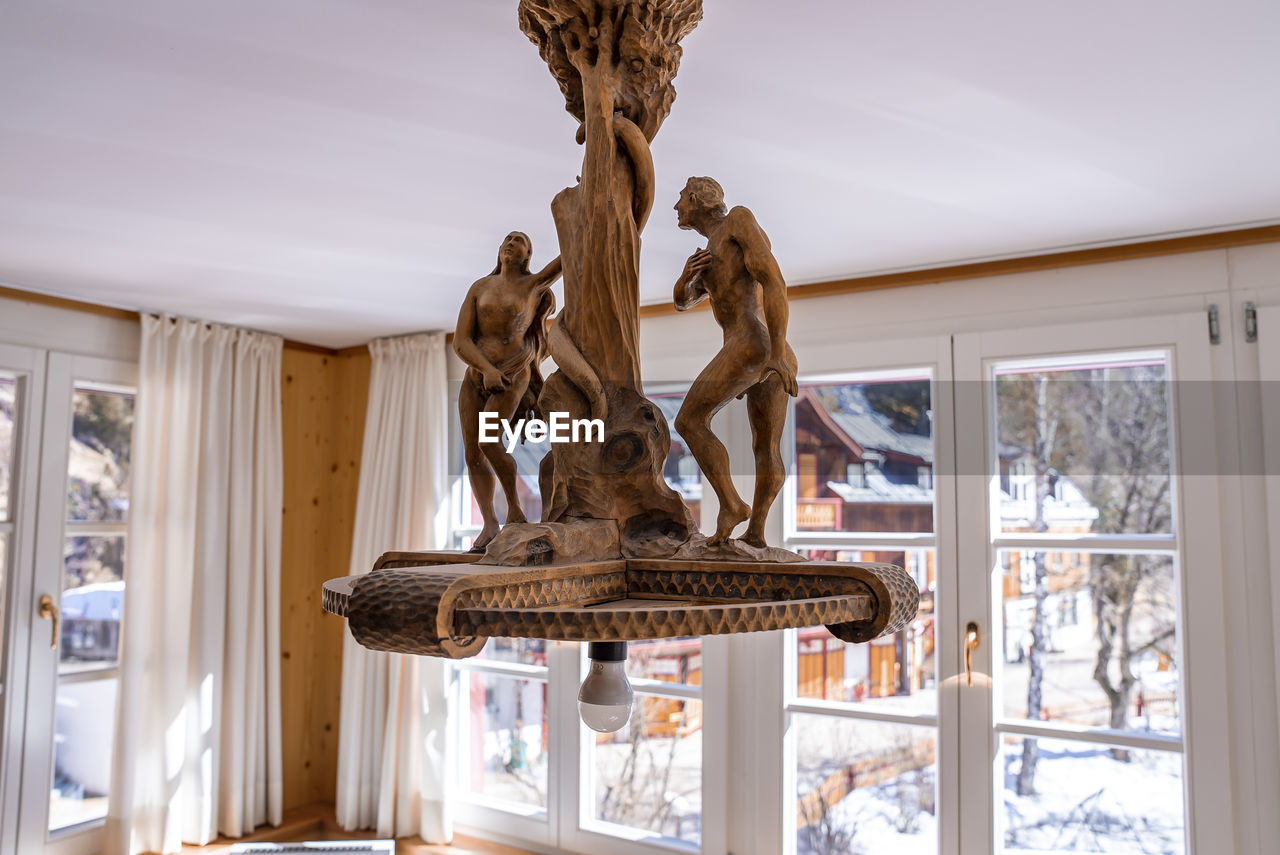 Ornate lighting fixture hanging from ceiling at resort during sunny day