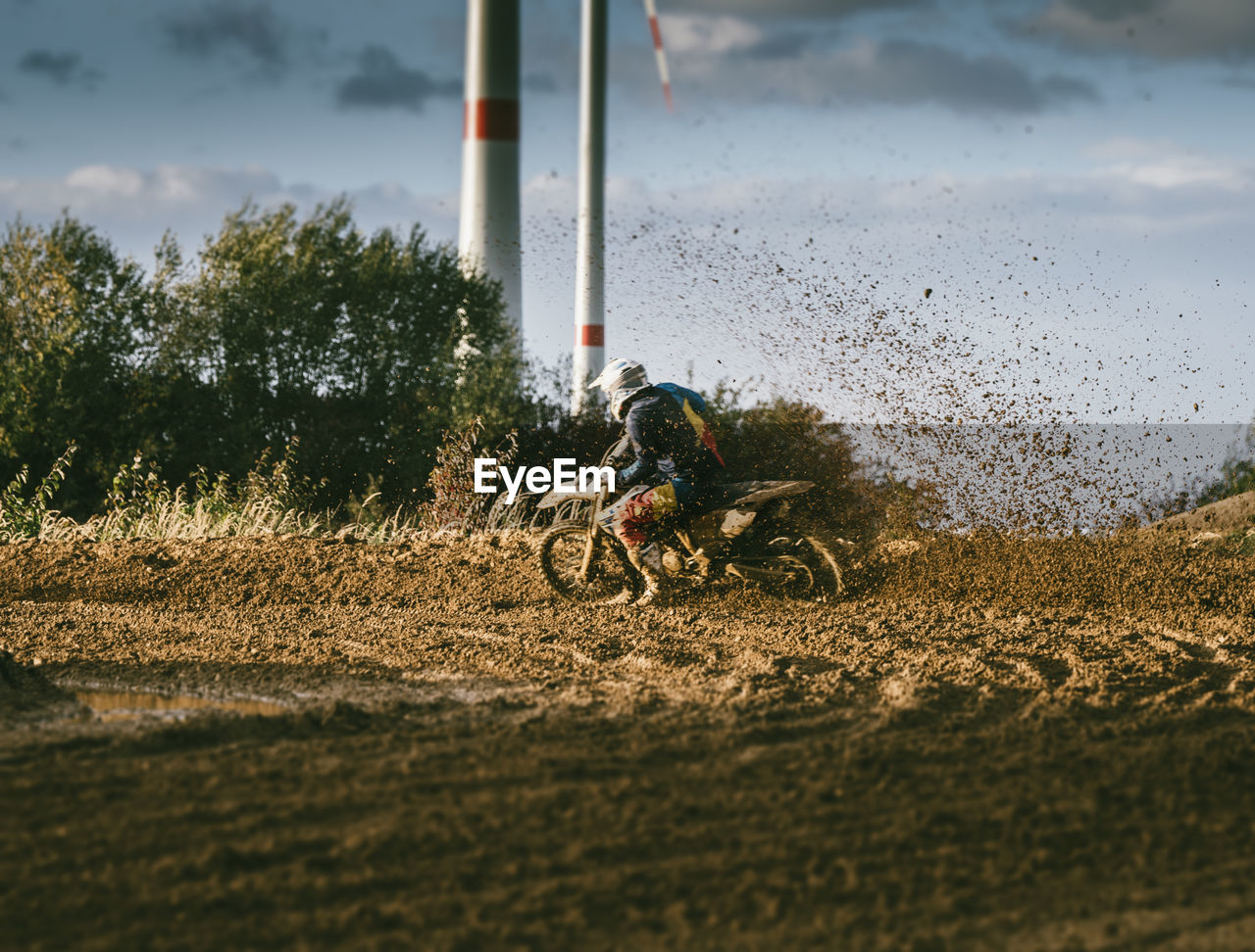 Man riding motorcycle on dirt road against sky