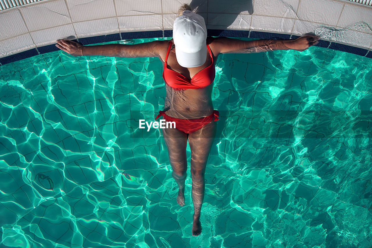 High angle view of woman wearing bikini relaxing in swimming pool