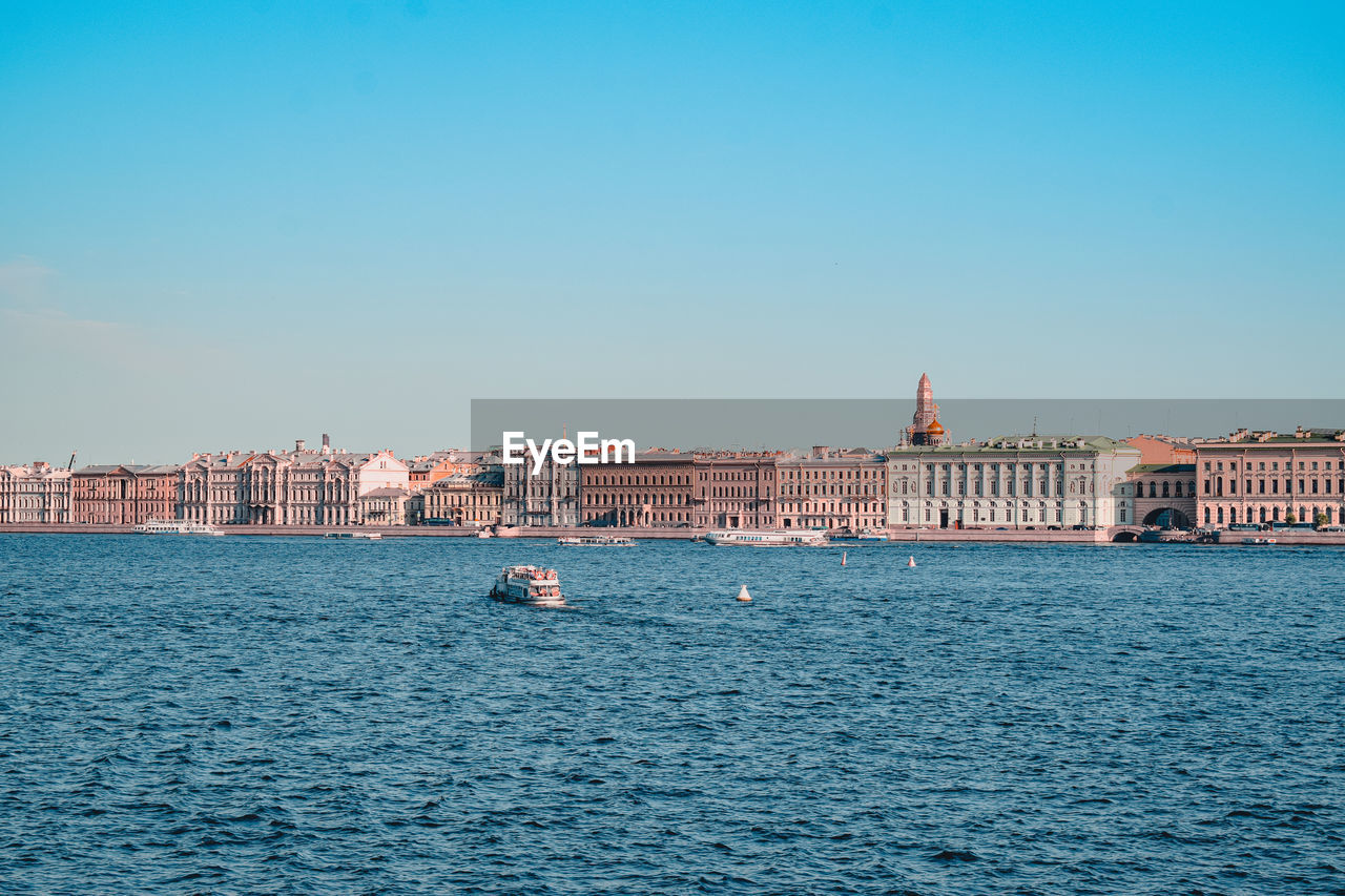 View of buildings by sea against blue sky