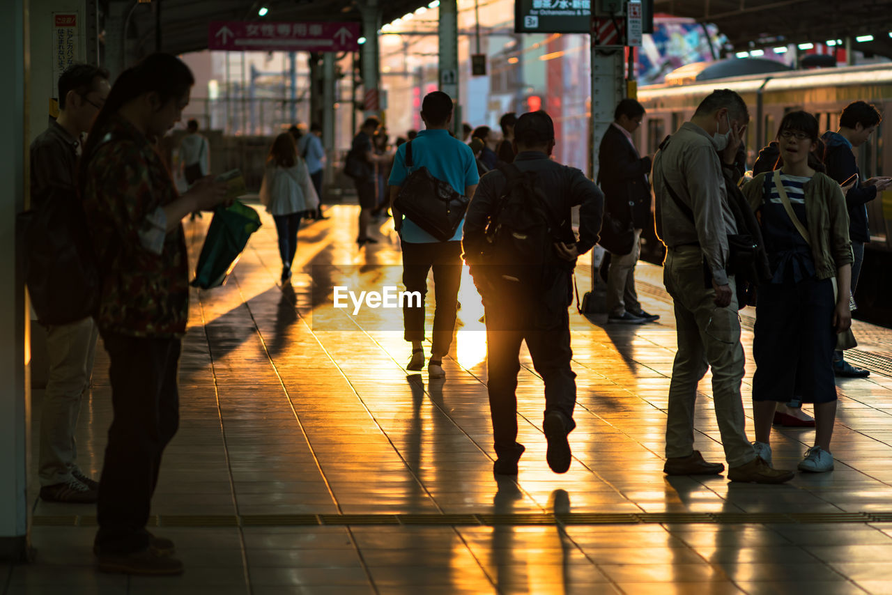 group of people, crowd, large group of people, transportation, city, architecture, walking, mode of transportation, travel, men, commuter, night, city life, adult, evening, women, public transportation, person, motion, lifestyles, outdoors, silhouette, clothing