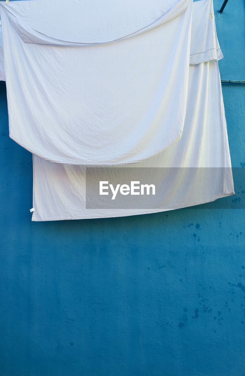 WHITE CLOTHES DRYING ON BLUE WALL