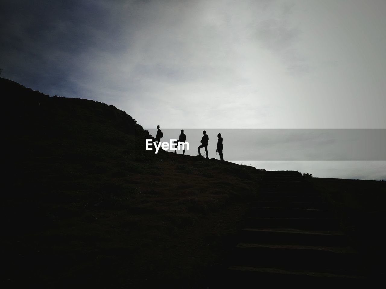 Low angle view of silhouette men hiking on mountain