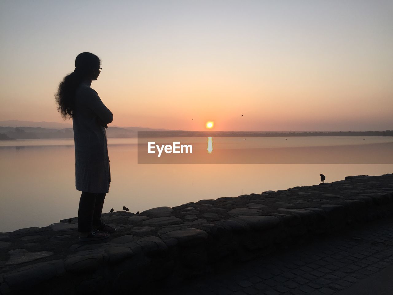 Woman standing on promenade against sky during sunset