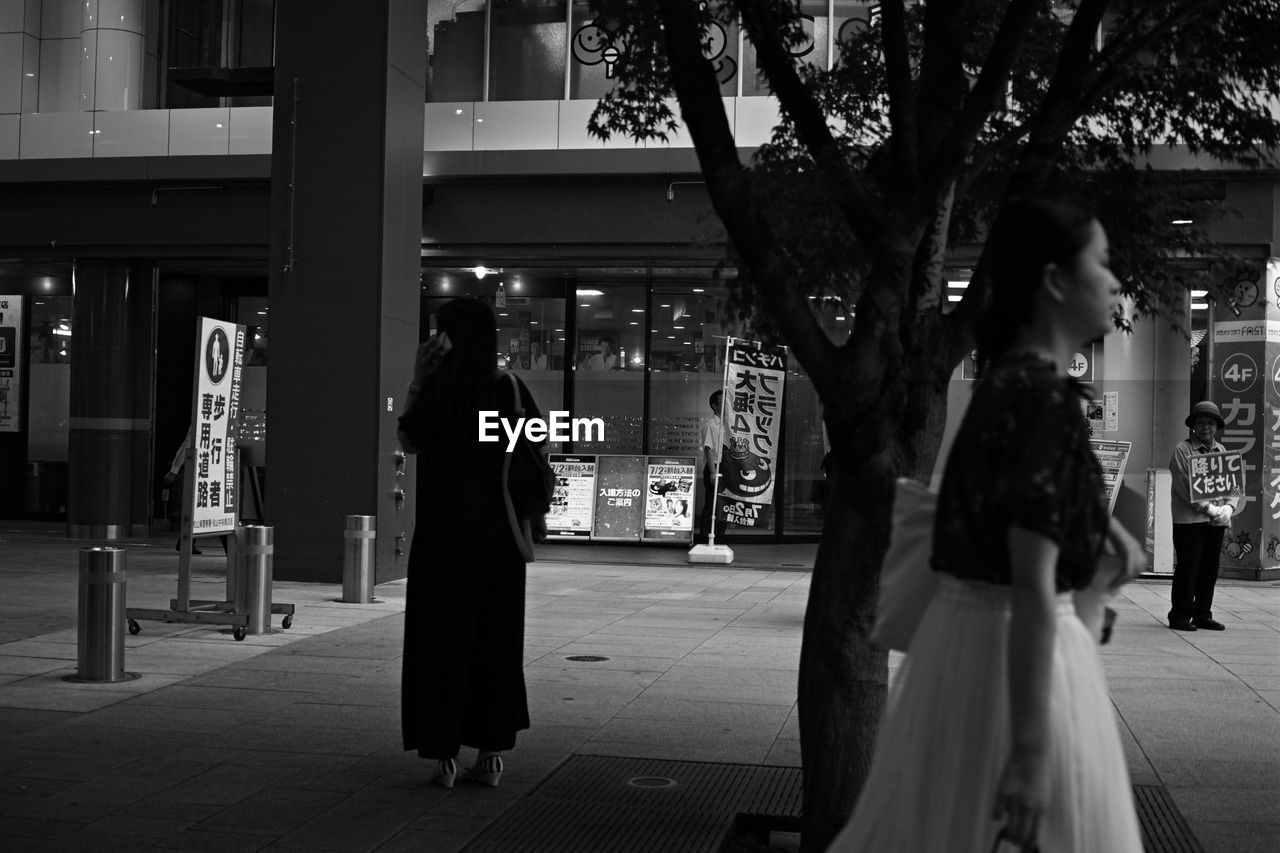 PEOPLE STANDING ON STREET AT NIGHT