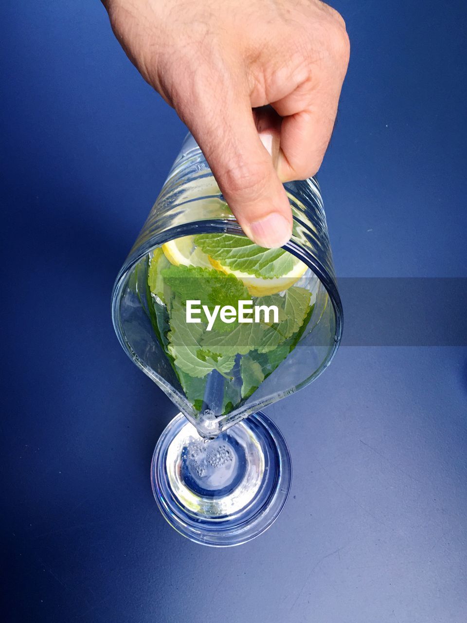 Human hand pouring water in drinking glass