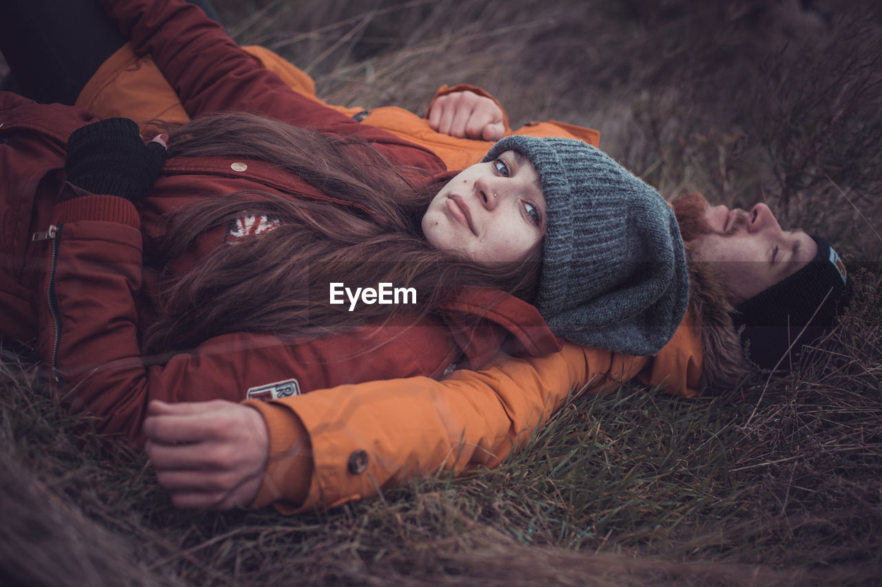 Portrait of woman lying on field with man outdoors