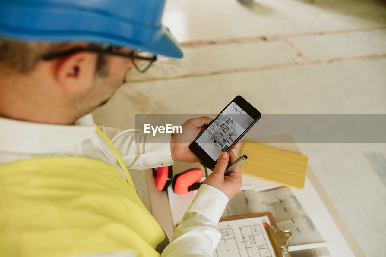 Foreman or architect working on mobile phone blueprints .construction site. home improvement