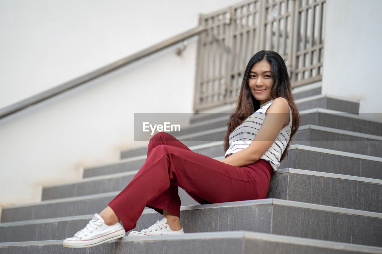 Low angle portrait of smiling mid adult woman sitting on steps