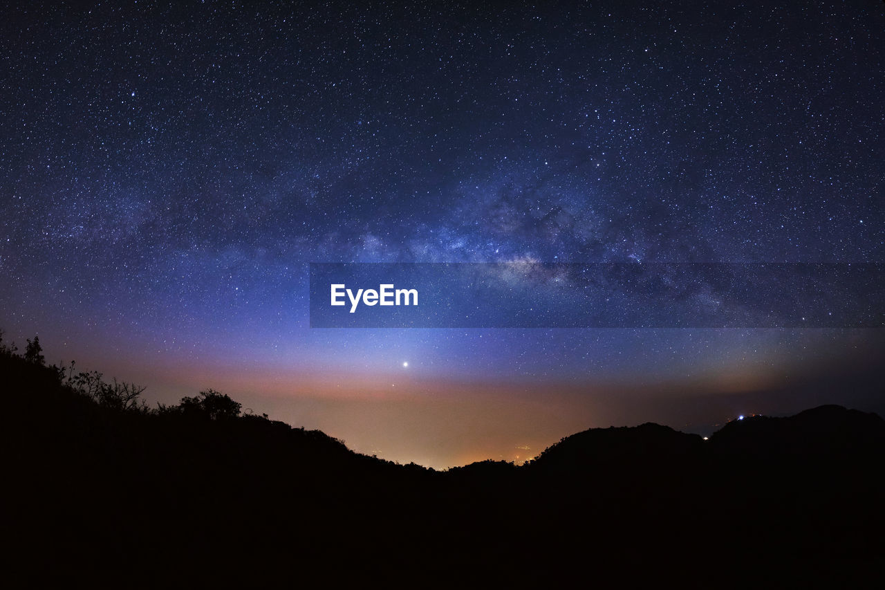 Scenic view of silhouetted mountains against star field