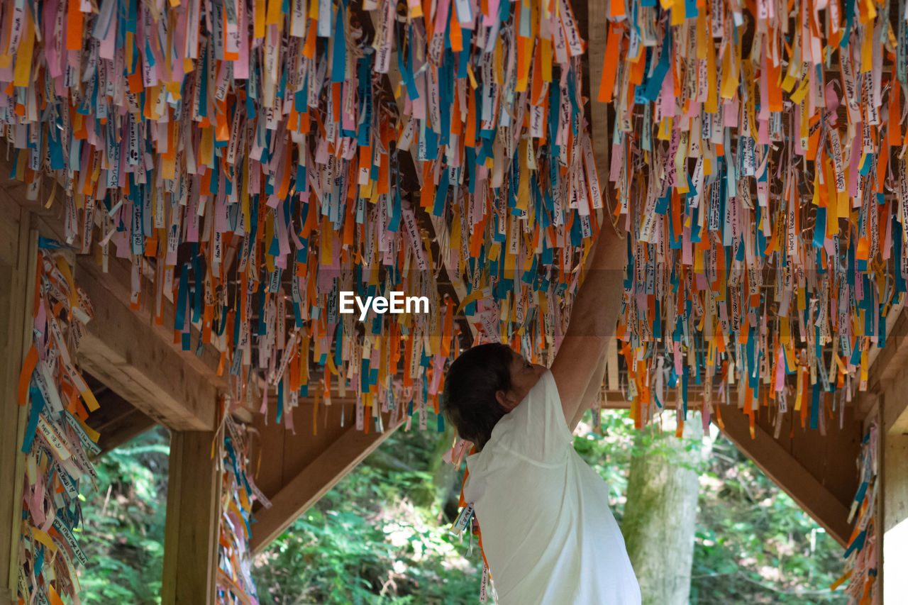 Senior man tying ribbon under wish of bridge