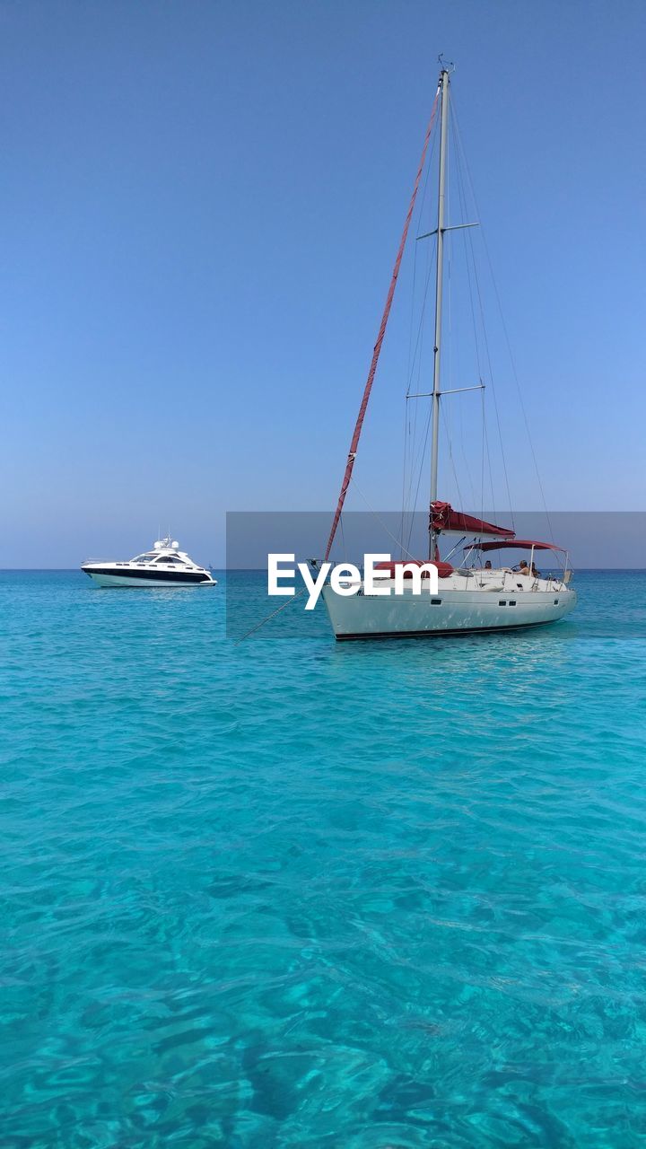 Sailboat and yacht in sea against sky