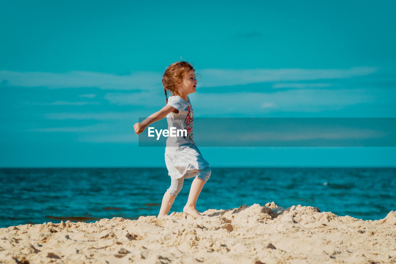 Full length of girl walking at beach against sky