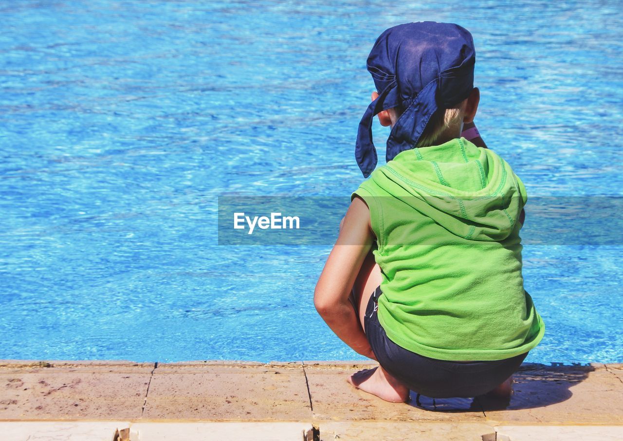 Rear view of boy looking at swimming pool