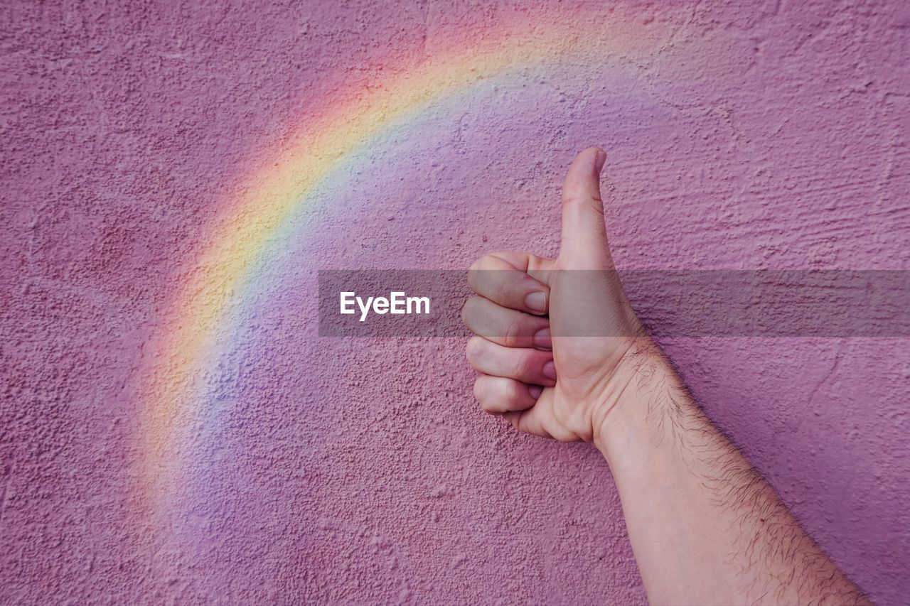 Hand with a rainbow on the pink wall. lgbt symbol