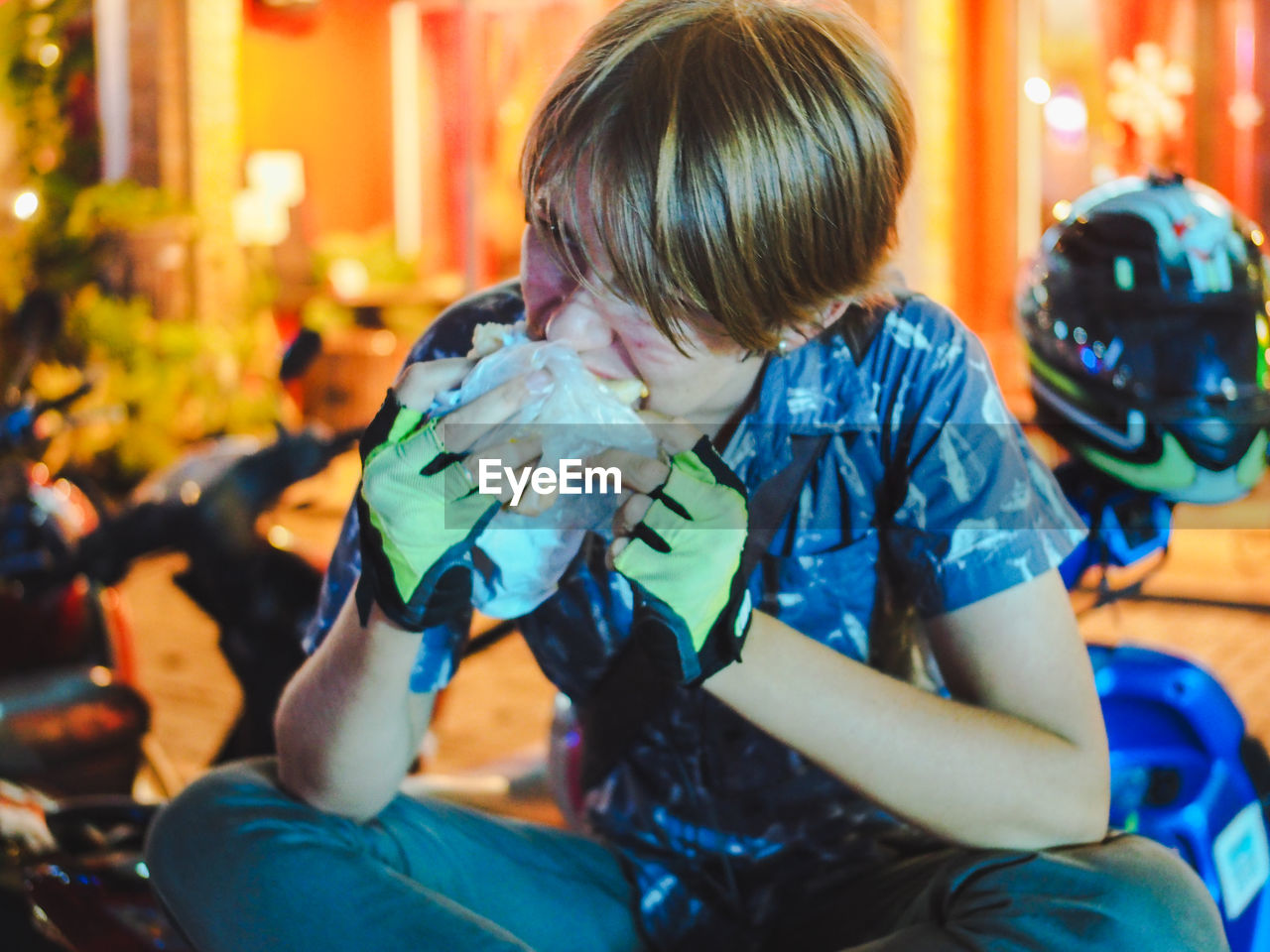 Young man eating sandwich while sitting on motor scooter outdoors