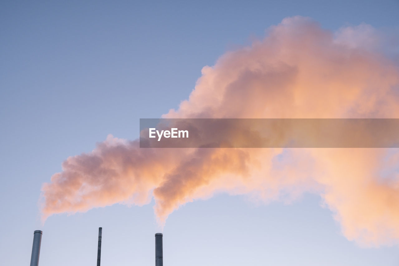 Low angle view of smoke stacks against sky