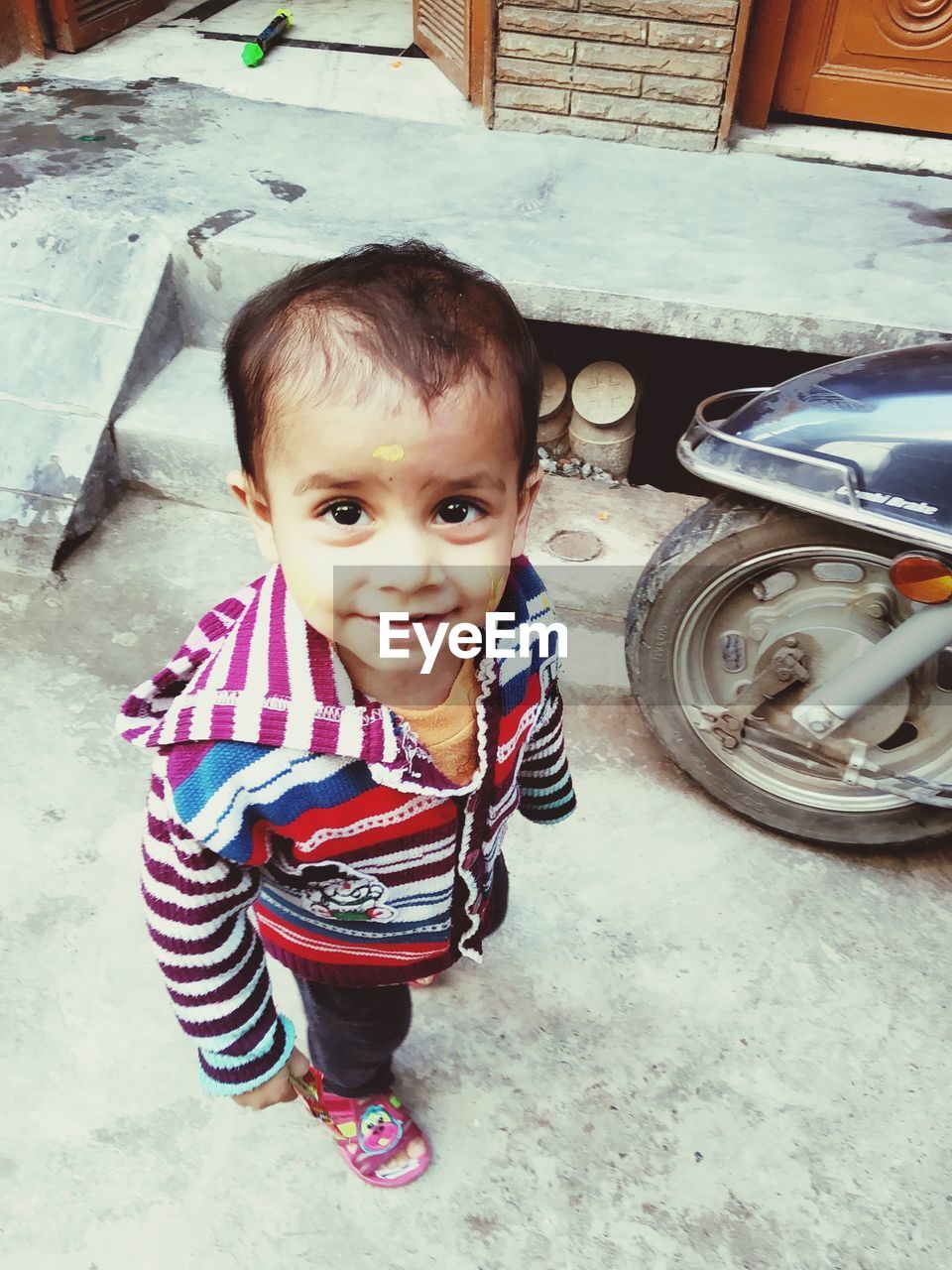 PORTRAIT OF CUTE BOY SMILING WHILE SITTING ON CAR