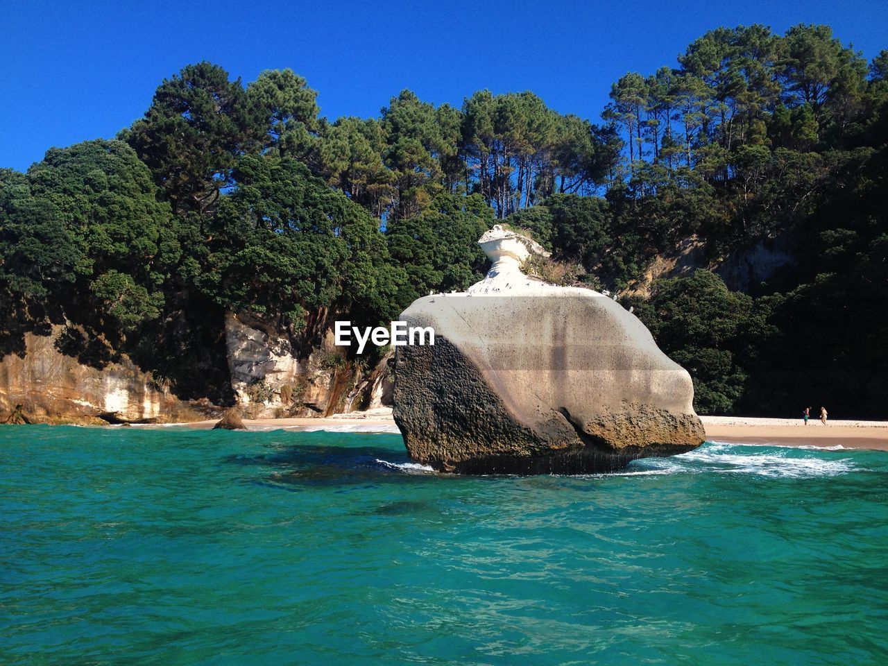 Rock formation in sea against clear blue sky