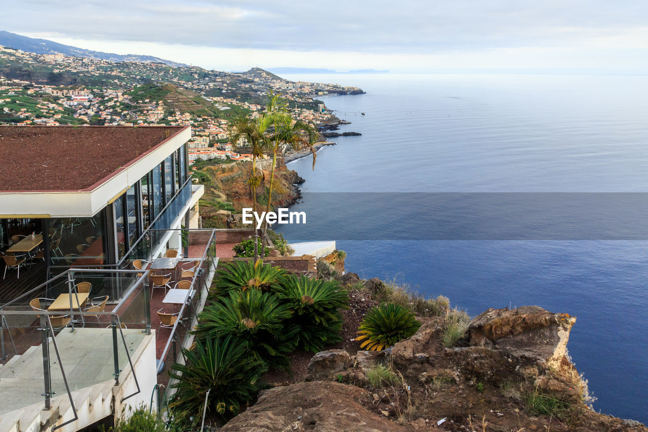 Aerial view of townscape by sea against cloudy sky