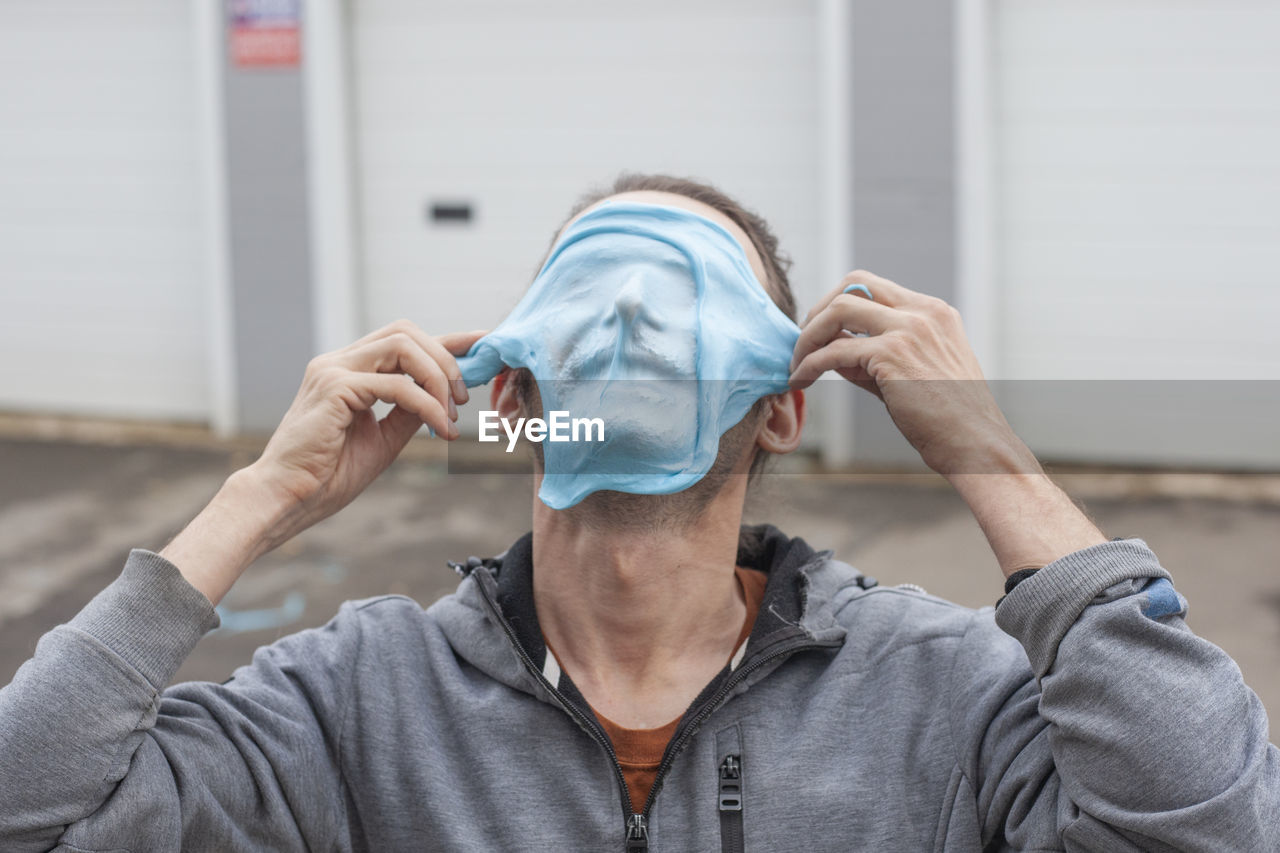 Close-up of man putting mask on face outdoors