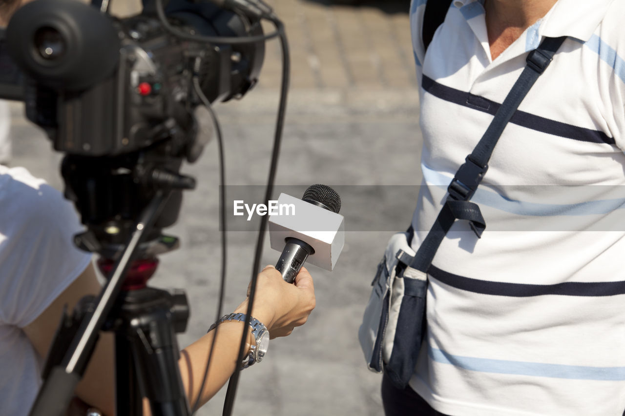 Midsection of reporter taking interview of man