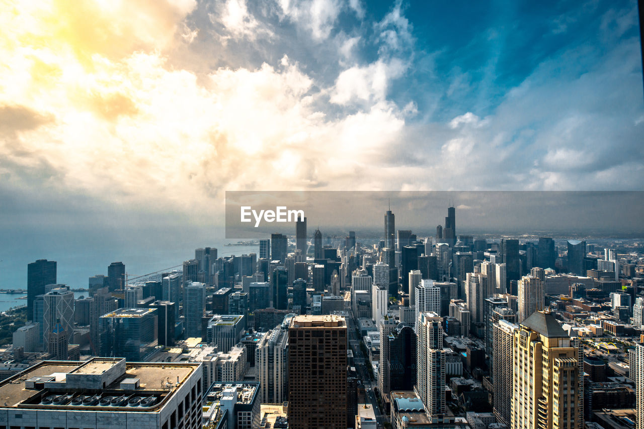 Aerial view of city buildings against cloudy sky