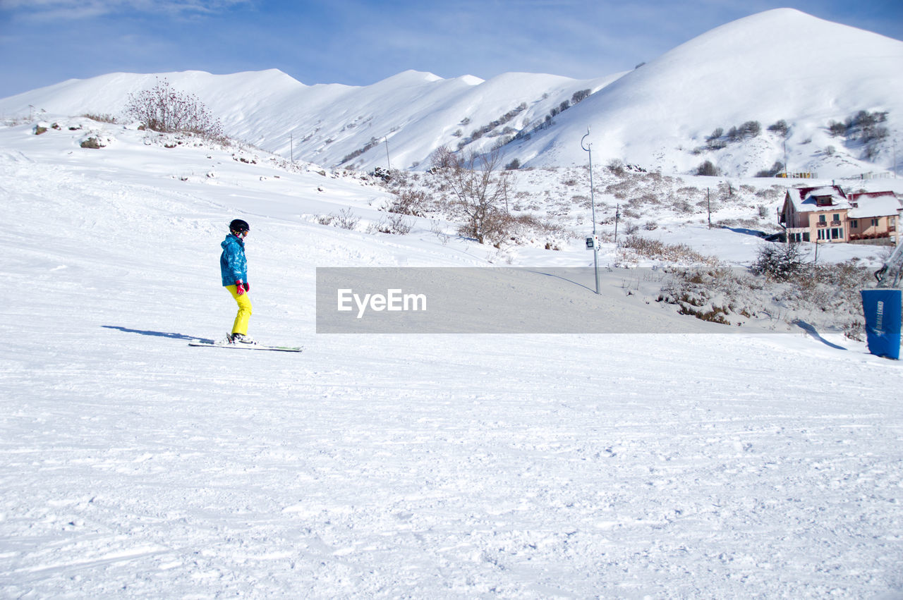 Rear view of man skiing on snow covered mountain against sky- gudauri ski resort